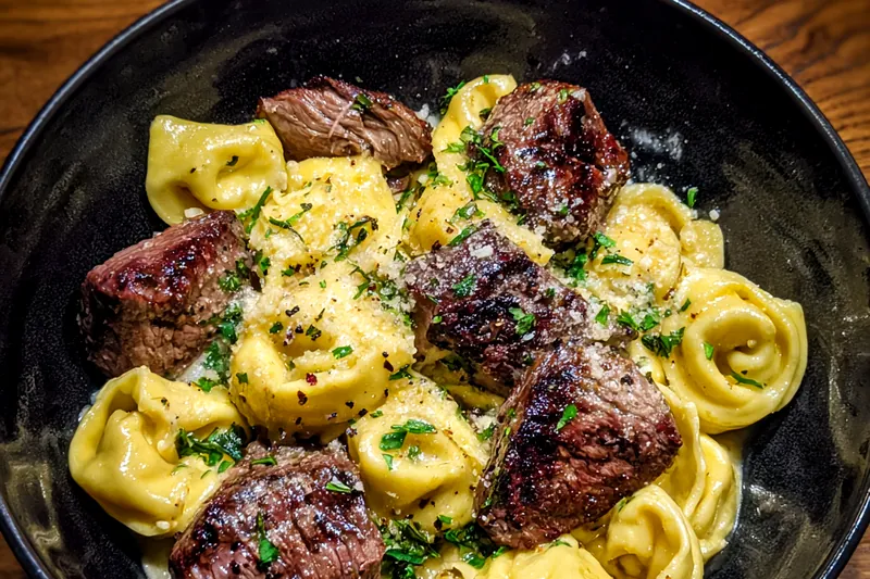 A colorful display of fresh ingredients for Creamy Garlic Steak Tortellini, including steak, tortellini, garlic, and herbs.