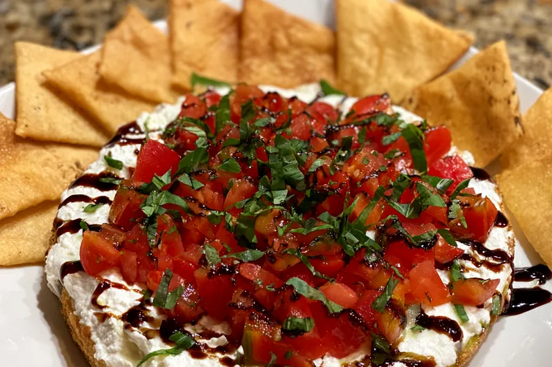 An assortment of fresh ingredients for Delicious Bruschetta Dip, including tomatoes, cheese, and herbs.
