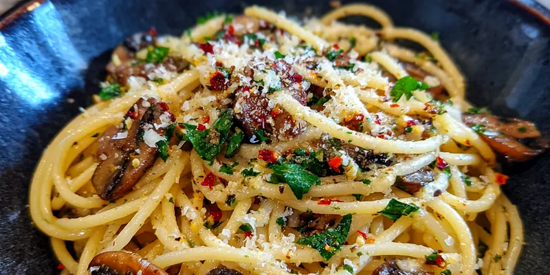 A beautifully plated Quick Garlic Mushroom Spaghetti topped with fresh parsley and served with a side of garlic bread.