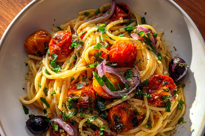 Chef Mitchell stirring Quick Vegan Mediterranean Pasta in a skillet, showcasing the vibrant colors of the dish.