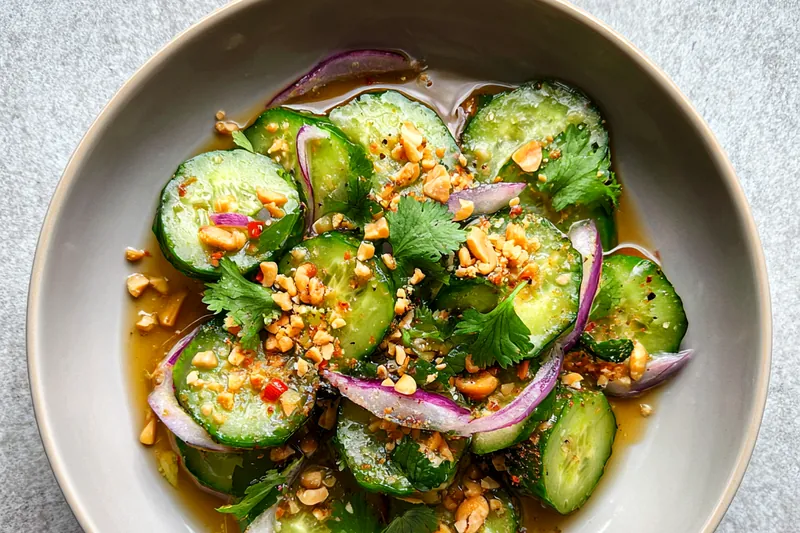 A selection of fresh ingredients for Refreshing Thai Cucumber Delight, including cucumbers, herbs, and dressing components.