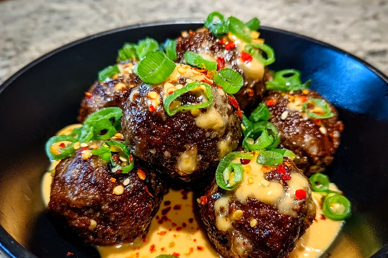 Chef Mitchell cooking Spicy Korean Meatballs Delight in the kitchen, showcasing the sizzling meatballs in the pan.
