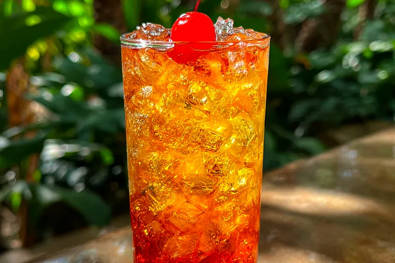 A close-up of a glass filled with Tropical Amaretto Punch Delight, showcasing the vibrant colors and garnishes.