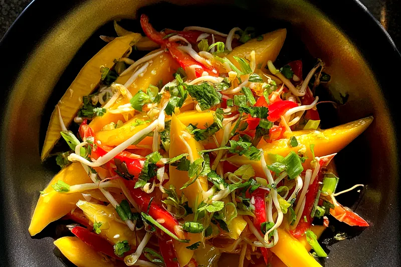 A vibrant display of fresh ingredients for Thai Mango Salad, showcasing ripe mango, colorful vegetables, and herbs.
